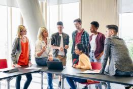 Groups of teachers sat and stood around a table in discussion